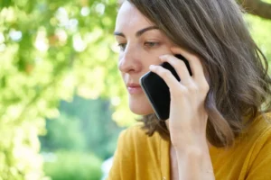 Mujer hablando por teléfono móvil con gesto pensativo