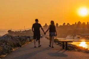 Pareja paseando de la mano junto al mar al atardecer