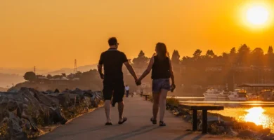 Pareja paseando de la mano junto al mar al atardecer